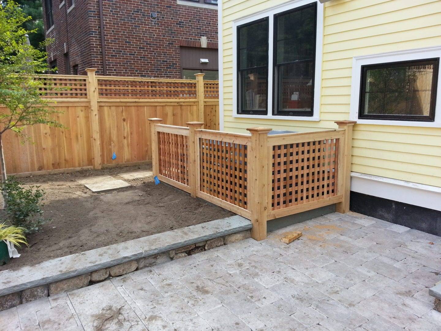 Functional and aesthetically pleasing outdoor space An outdoor patio area with a custom wooden railing and a partial view of a house