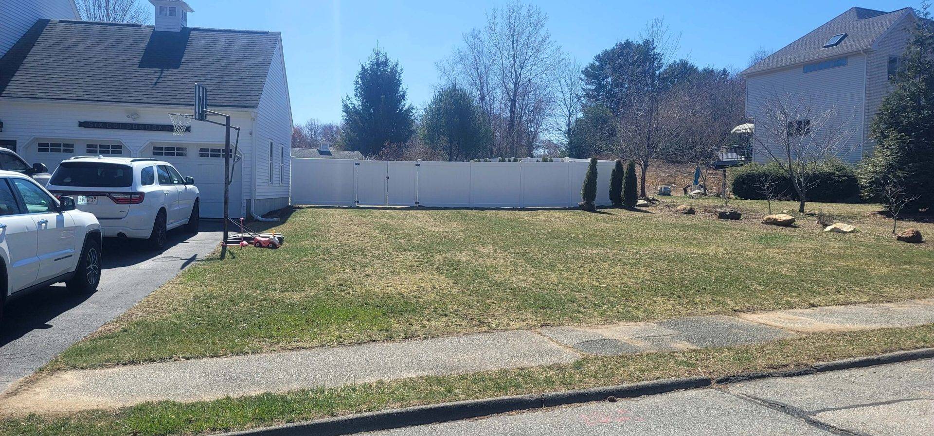Typical sub-urban scene with a classic white picket fence Sub-urban scene with a white picket fence, a house and a yard