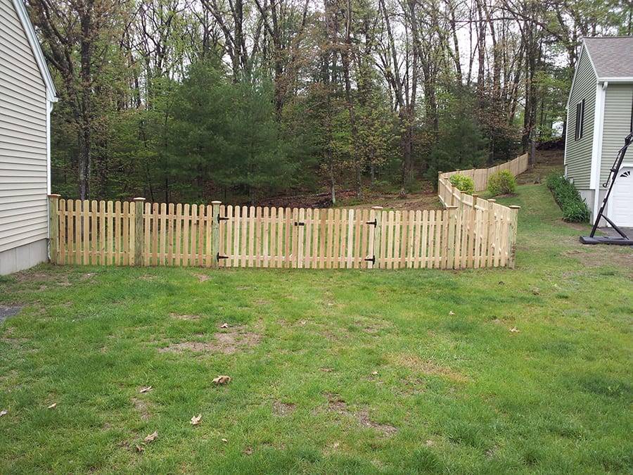Light colored wooden fence enclosing a grassy area with trees Light colored wooden fence enclosing a grassy area with trees