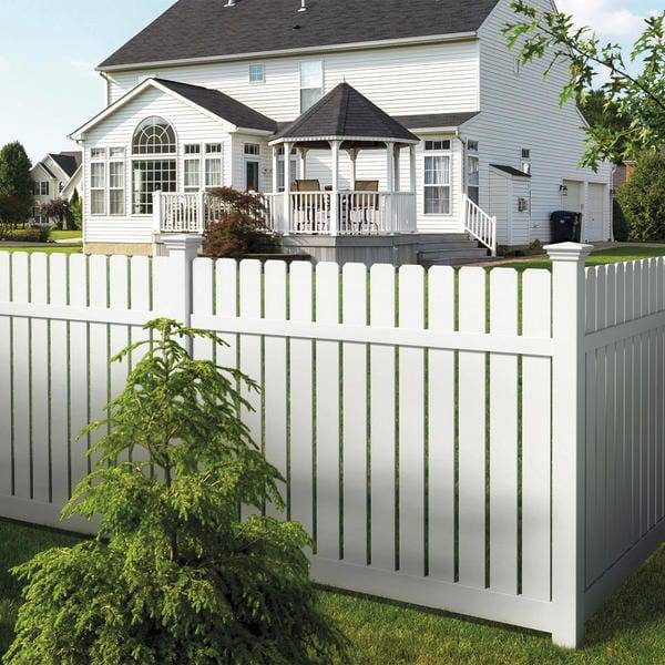 A white picket fence in the foreground White vinyl Fence in the foreground with a house and partially visible porch