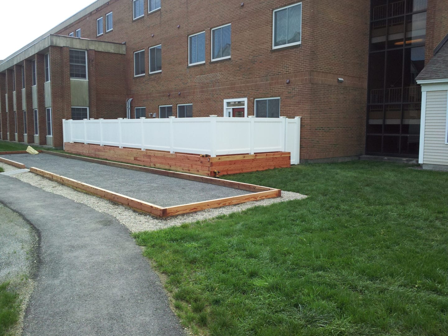 A white fence stands in front of a building, creating a clear boundary between the structure and the surrounding area.