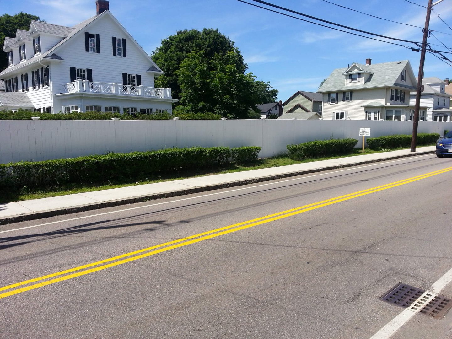 A white fence with yellow stripes alongside a road, providing a clear boundary and visual contrast.