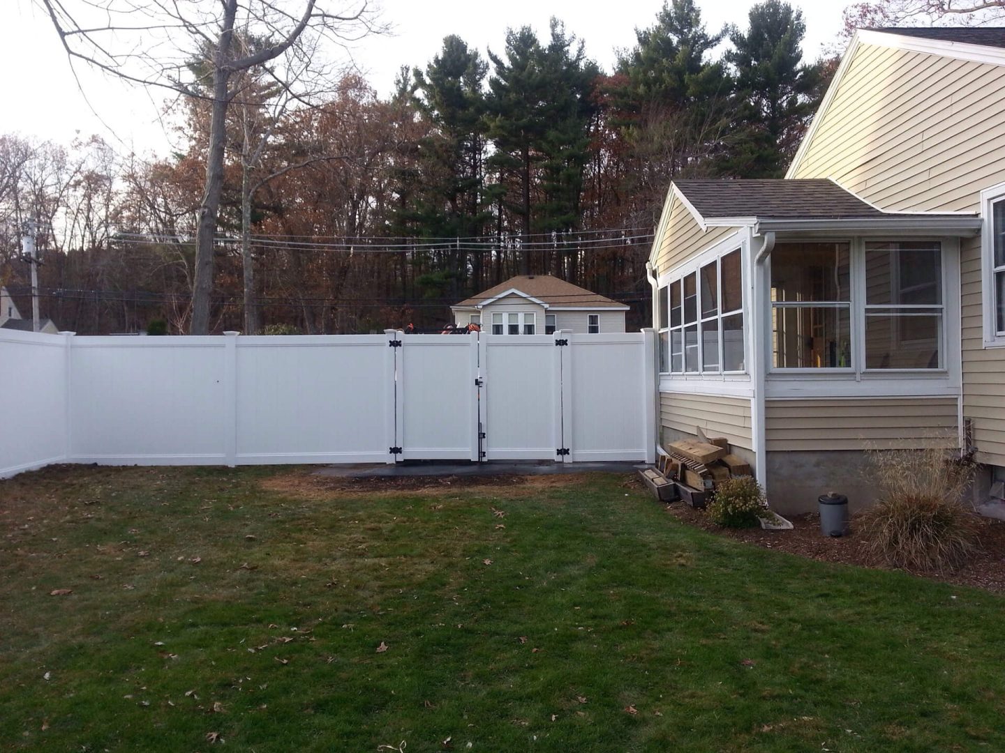 A white fence stands in front of a house, framing the property and enhancing its curb appeal.