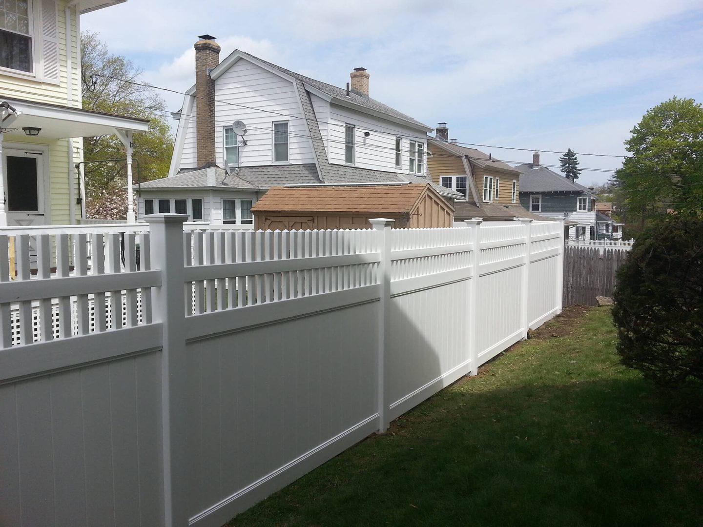 A white fence stands in front of a house, framing the property and enhancing its curb appeal.