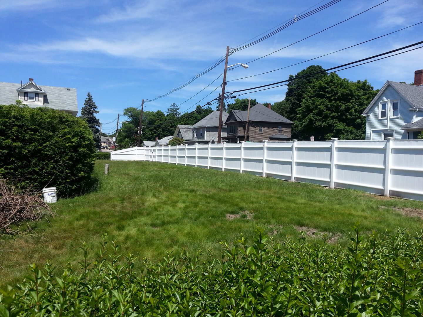 A white fence stands in front of a house, framing the property and enhancing its curb appeal.