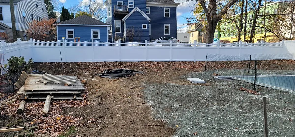 A white vinyl fence in a privacy type with open scallop spindle top